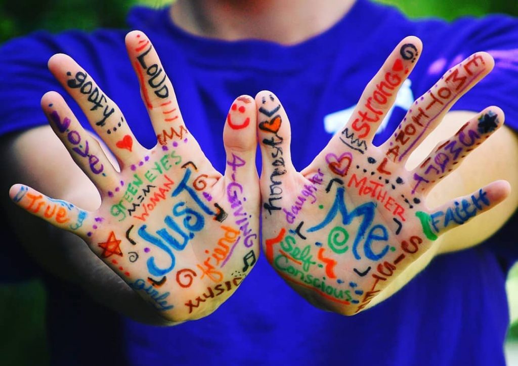 immagine contro stigma sociale: due mani con tante scritte "just me"
